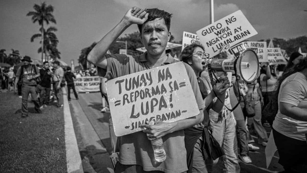 Protesters hold signs demanding land reform.